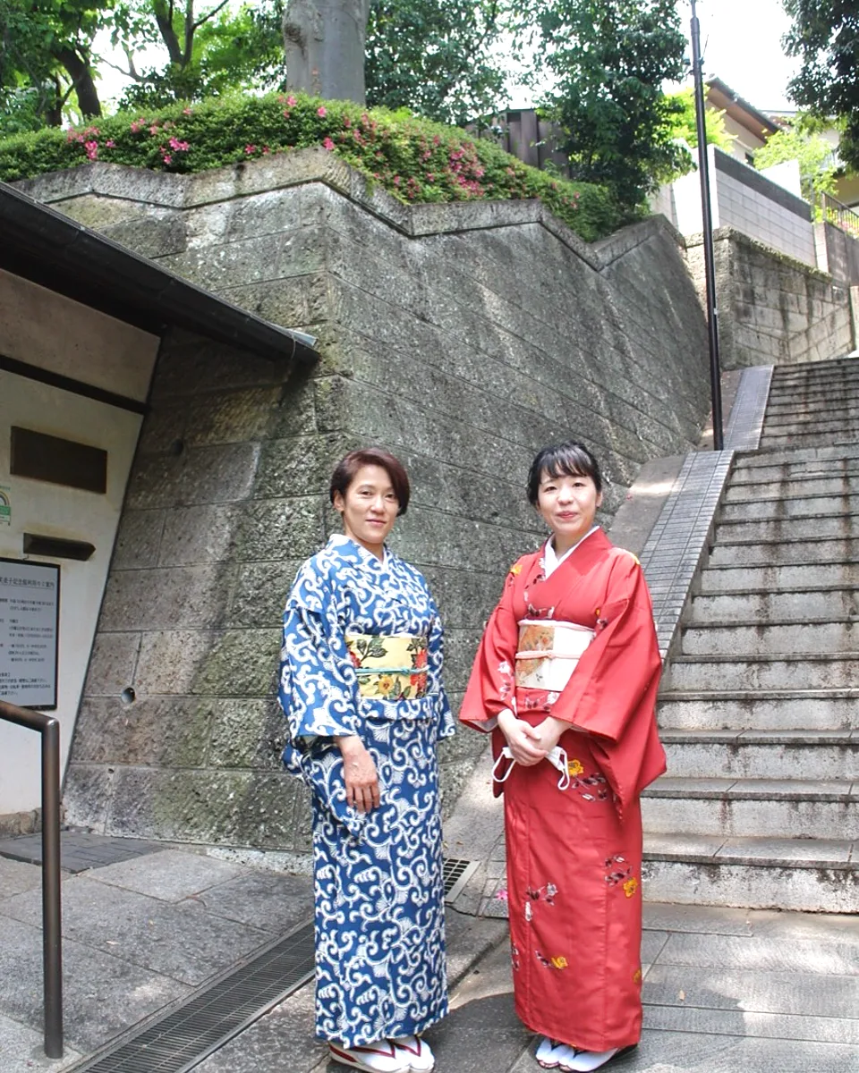 Two guests wearing kimono beside a stone stairway in Tokyo